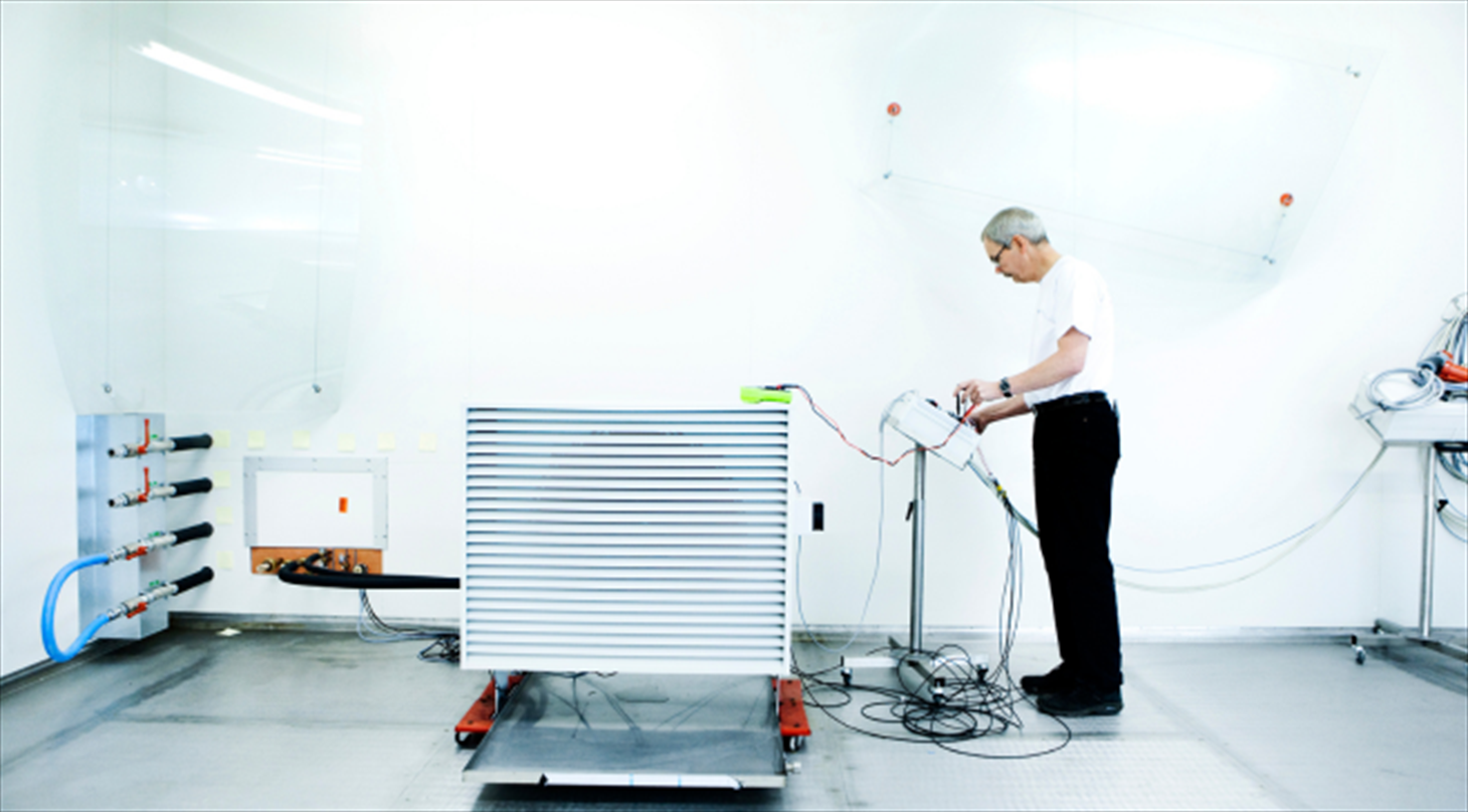 A test engineer working on test equipment connected to a heat pump in the Heat Pump Test Laboratory at Danish Technological Institute.